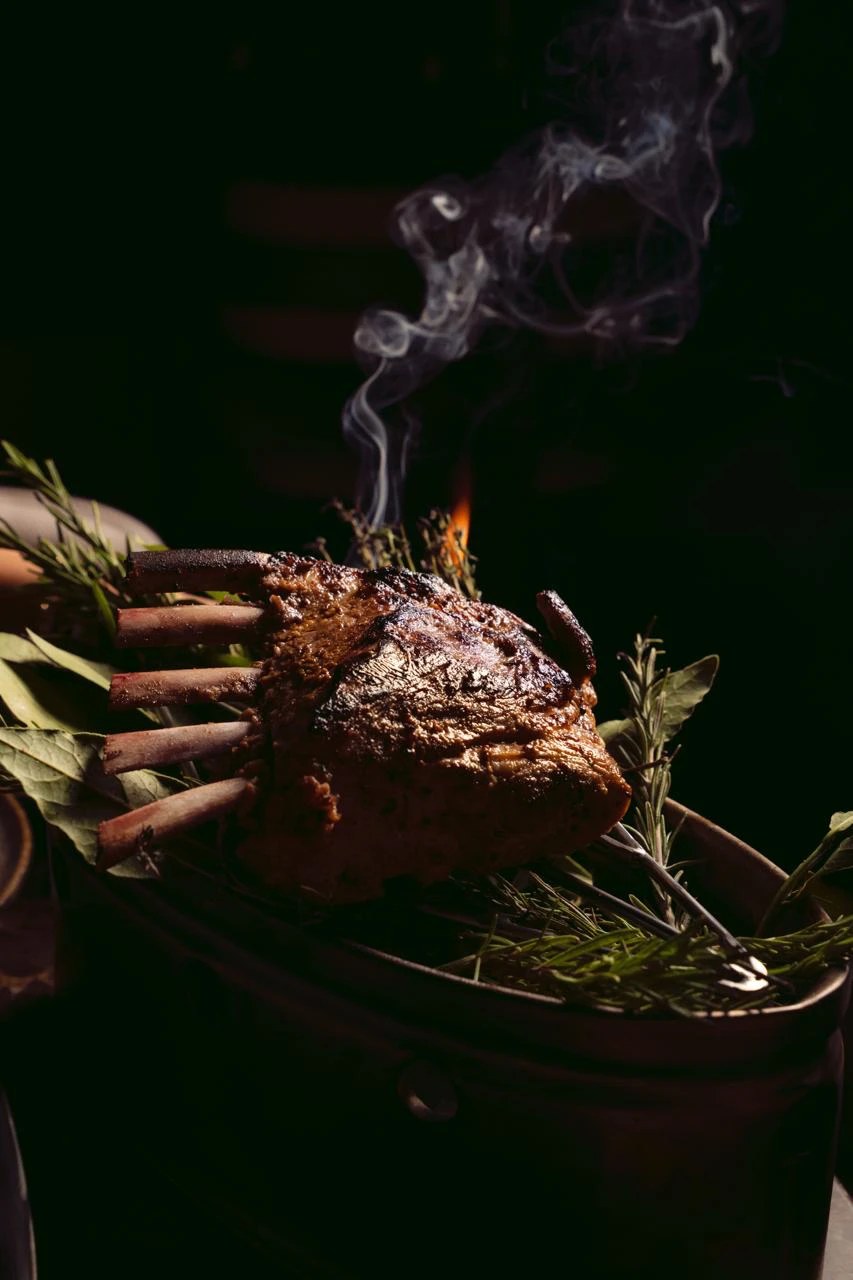 Carré de viande rôti et fumant, entouré d’herbes